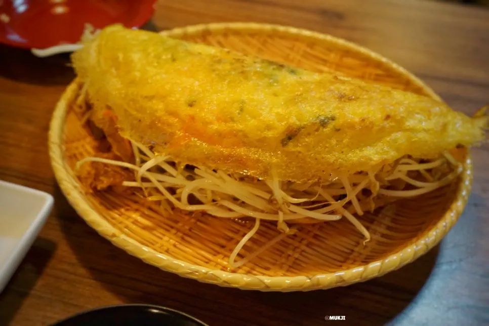 Banh xeo packed full inside with lettuce and rice paper on the side