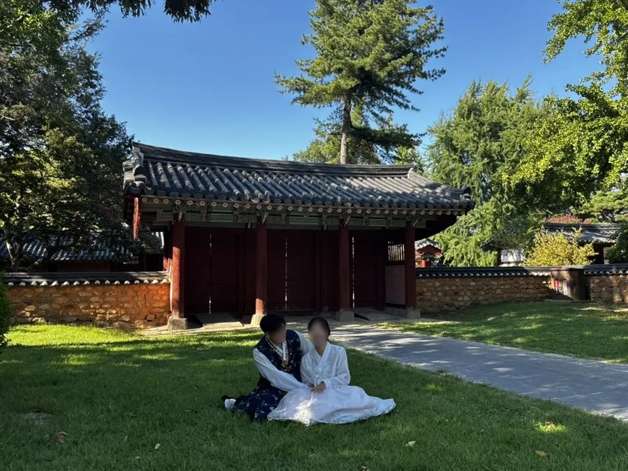 Couple snap seated on the grass at Gyeonggijeon