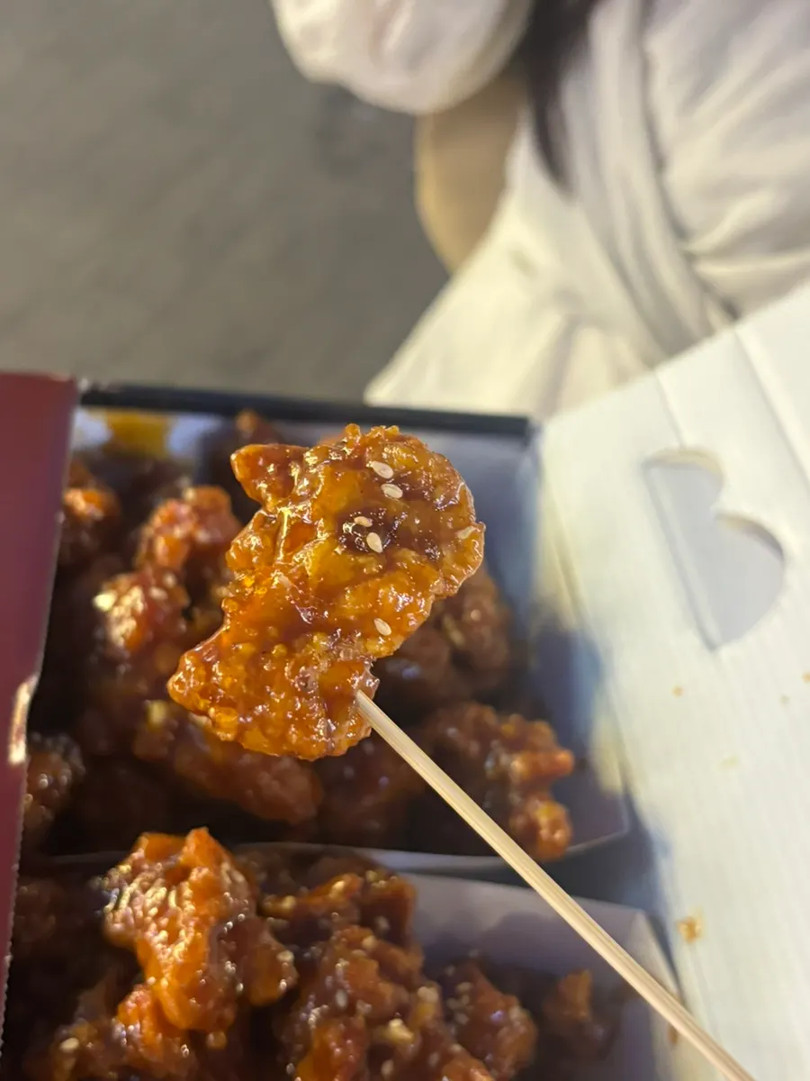 간장맛 닭강정 한 조각을 집어 든 모습