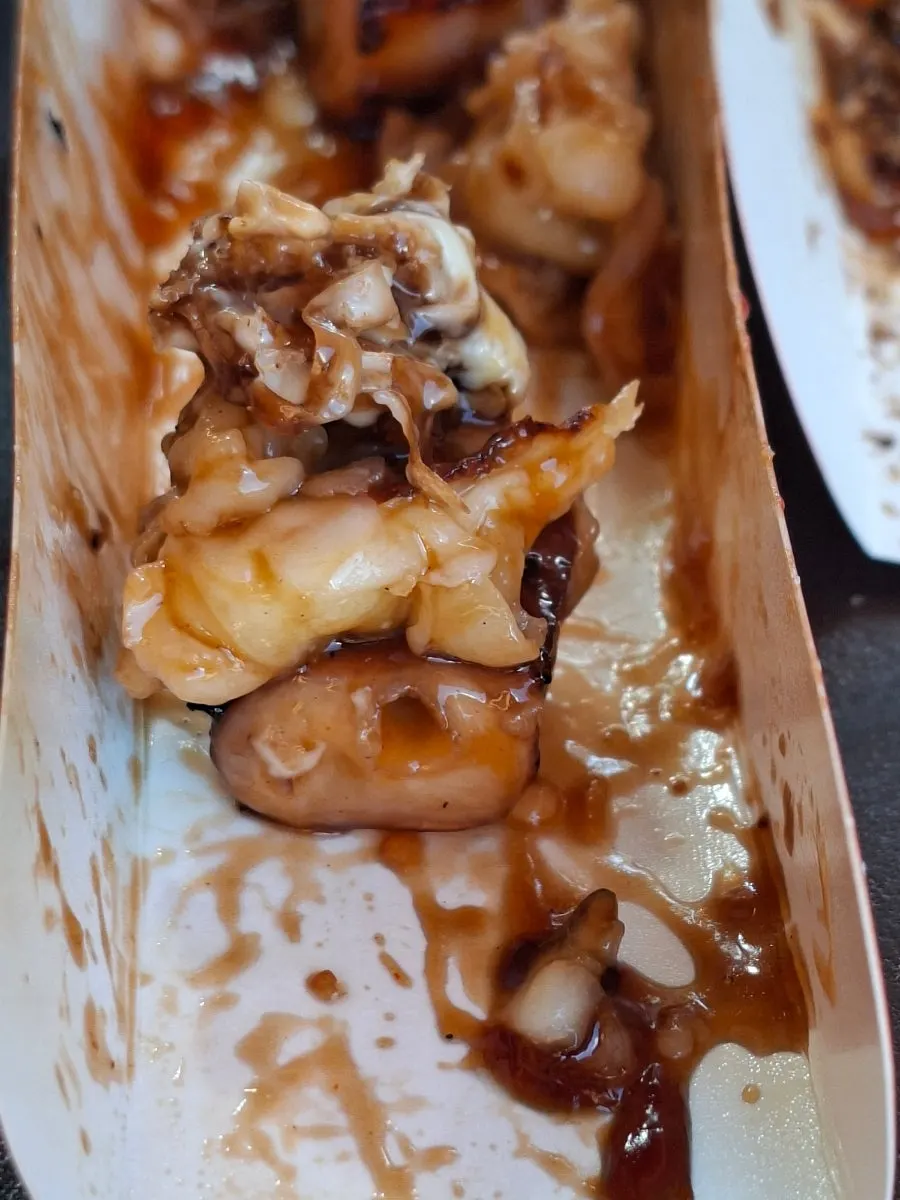 Hands holding an octopus skewer and a slushy together