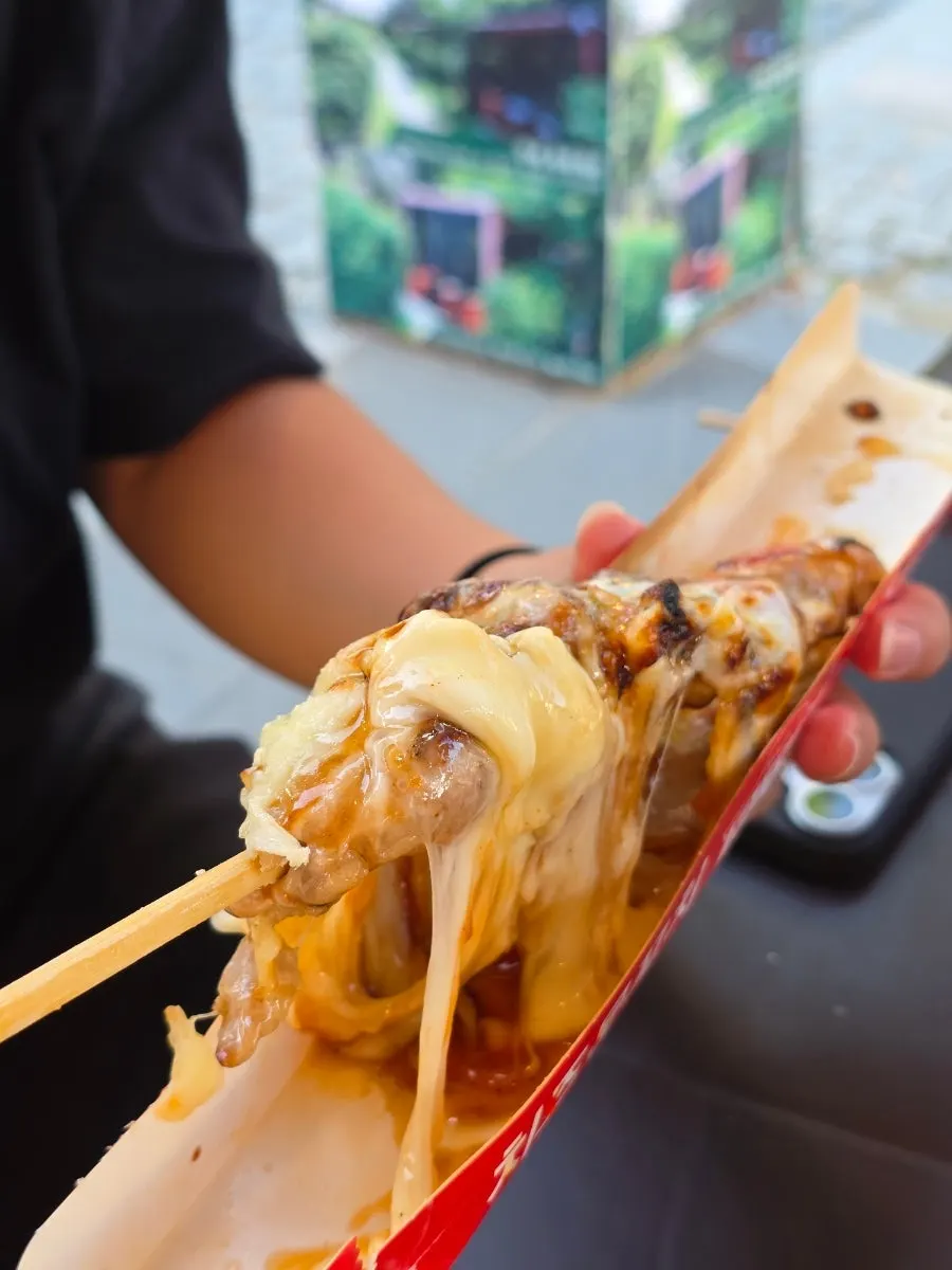 Bocado de brocheta de pollo con el queso estirándose