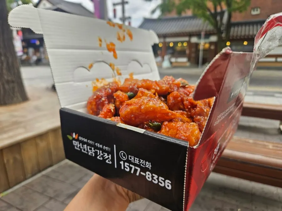 Eating the dakgangjeong and shrimp gangjeong on an outdoor chair