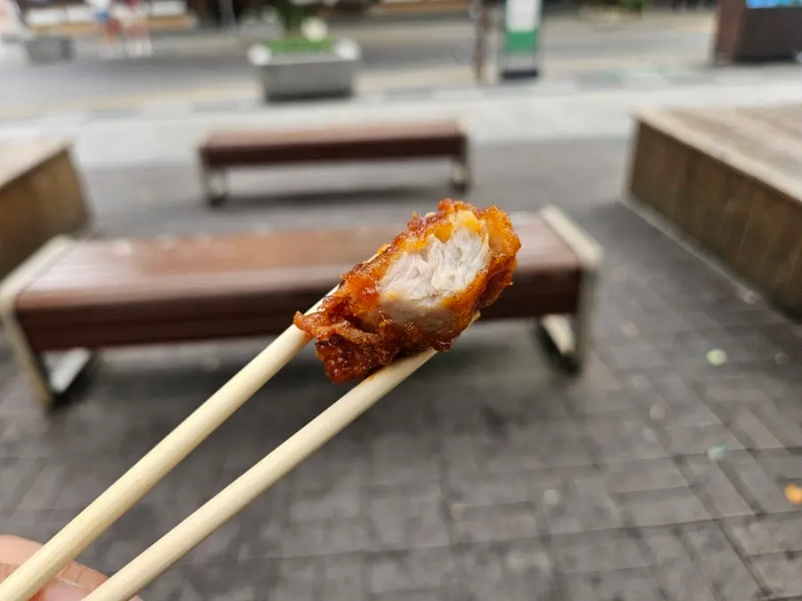 Piece of spicy dakgangjeong coated in thick, sticky sauce
