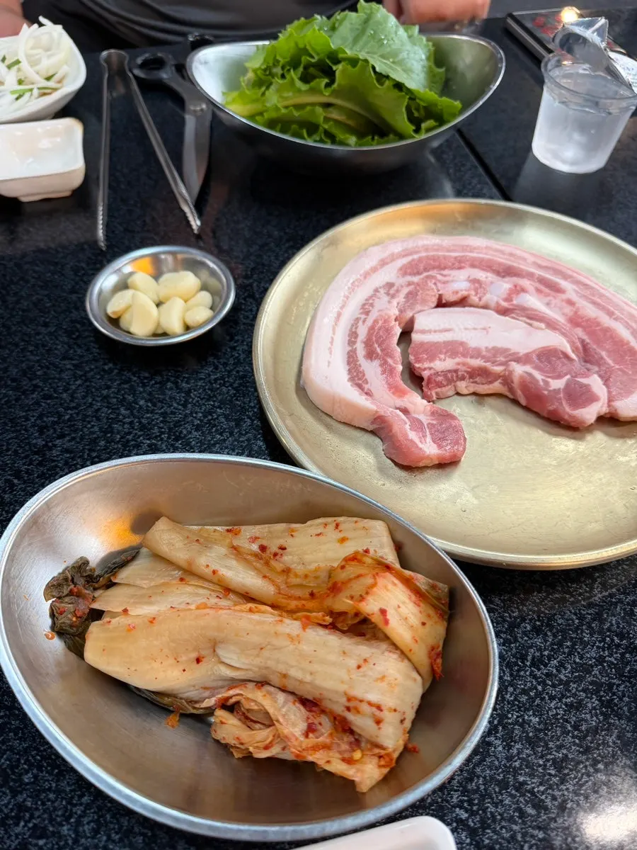 Two servings of pork belly cooking on the cast-iron lid