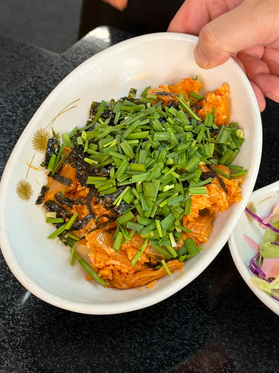 A spoonful of kimchi stew with aged kimchi, meat, and tofu