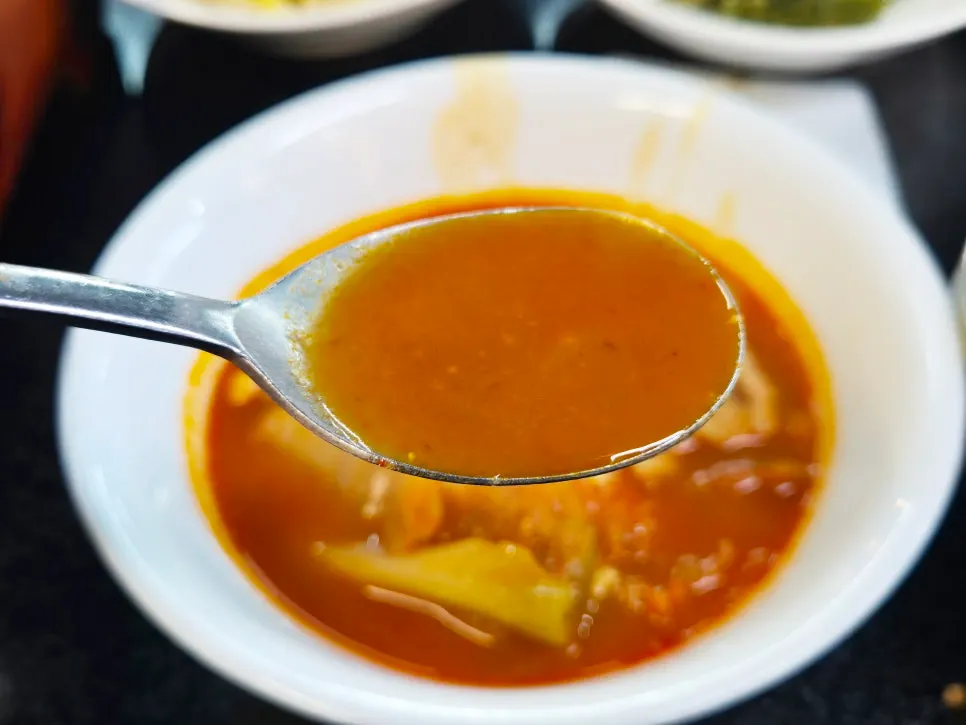 A ladle scooping up the rich kimchi stew broth