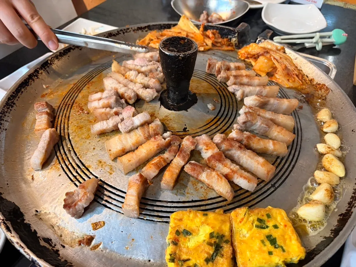 Pork belly and aged kimchi grilling on Jeonju House's cast-iron lid