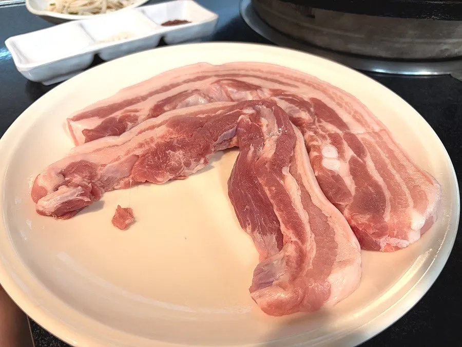 Fresh pork belly placed on the cast-iron lid pan