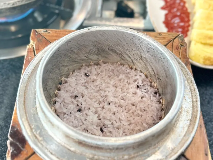 Rice scooped into a bowl with the pot for making sungnyung