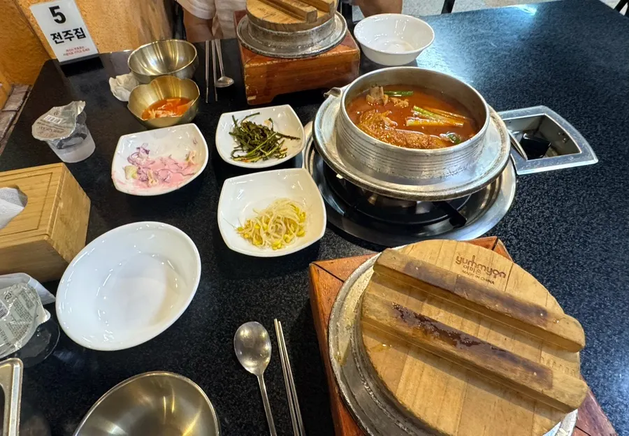 Full table spread with side dishes, cast-iron pot rice, and stew