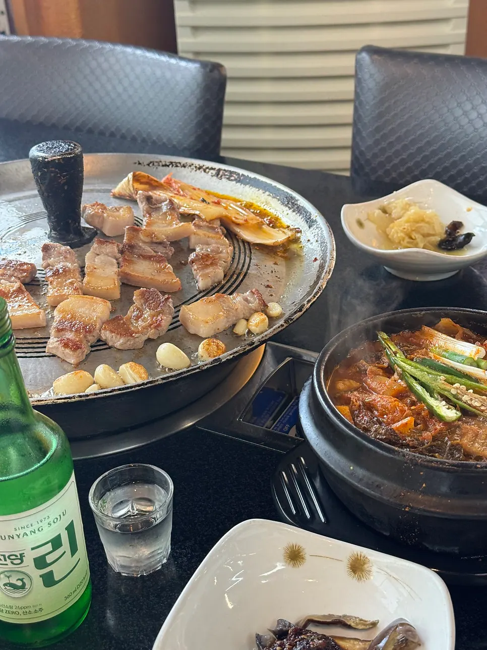 摆有五花肉、泡菜汤和烧酒的整桌菜品