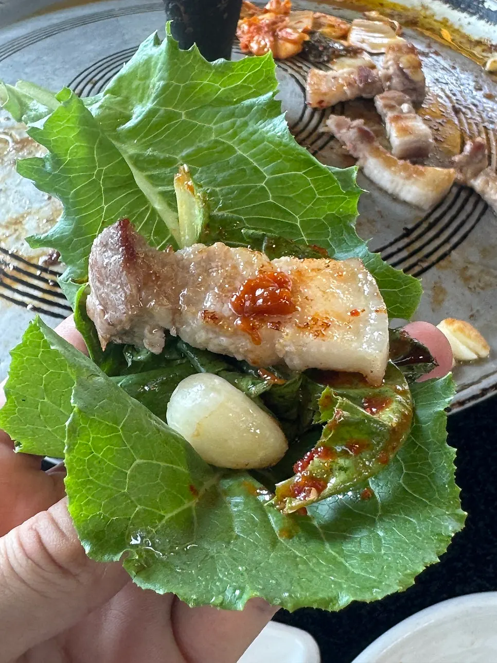 包着蒜片和烤泡菜的五花肉包菜