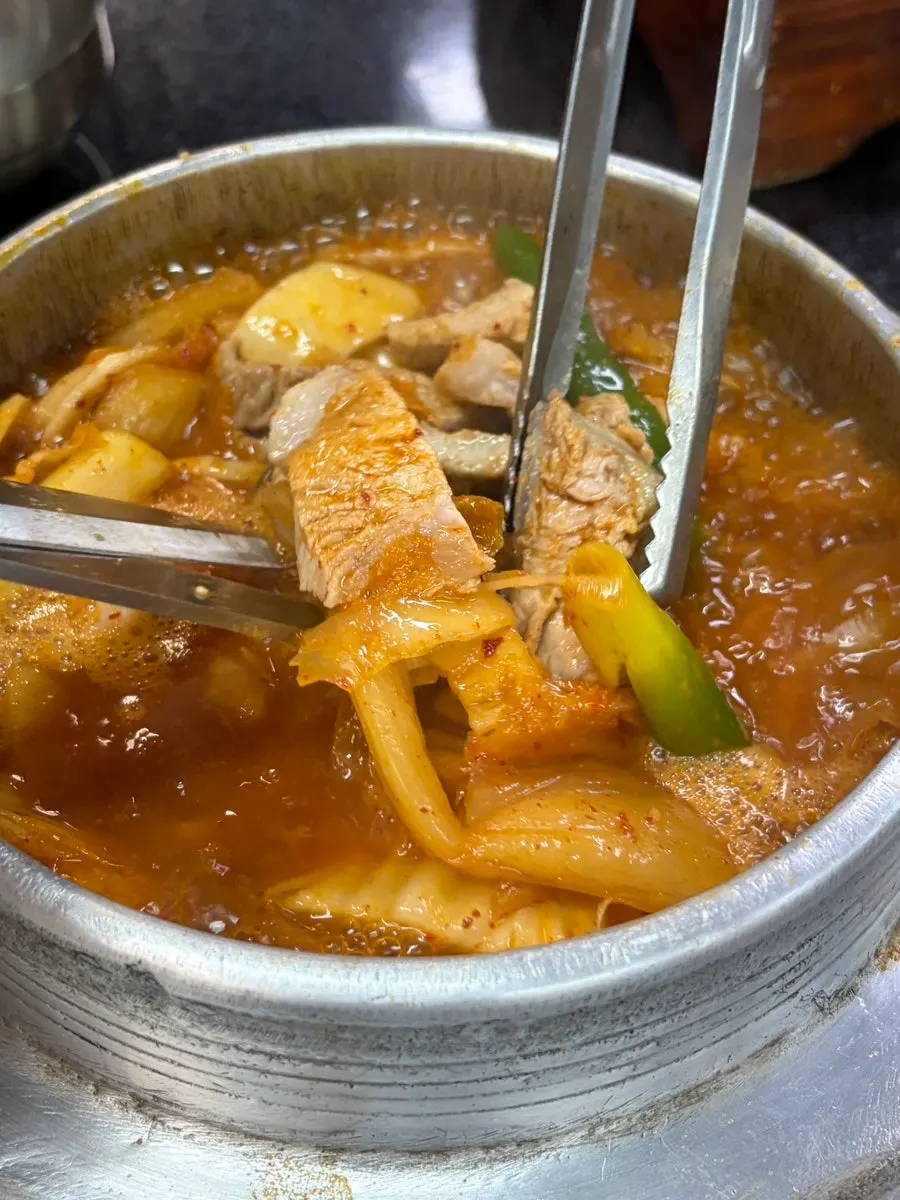 A ladle of rich galbi kimchi stew broth