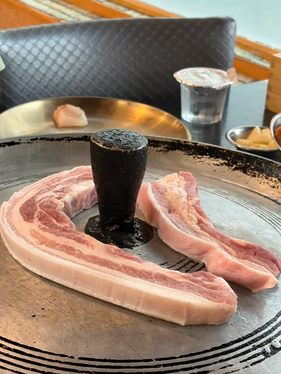 Fresh pork belly cooking on the cast-iron lid