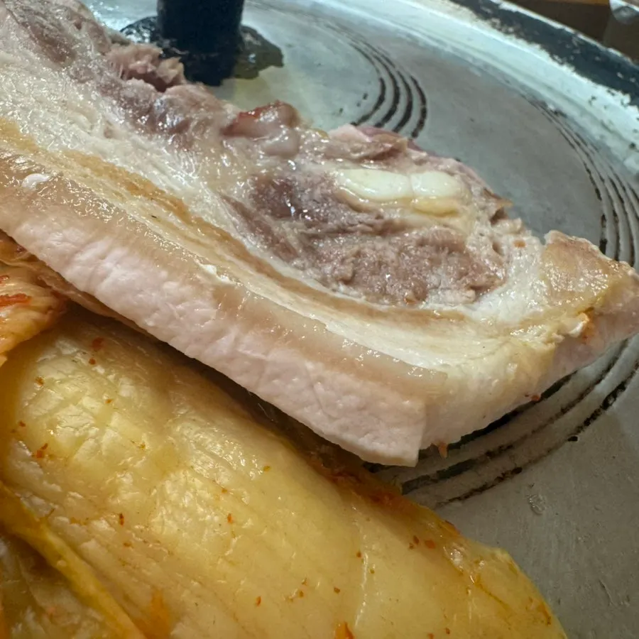 Pork belly, aged kimchi and garlic piled on the cast-iron lid