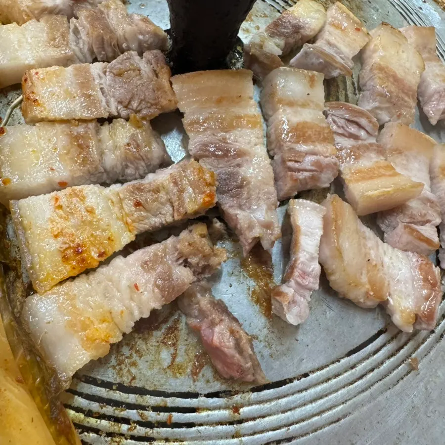 Thick fresh pork belly cooking on the grill