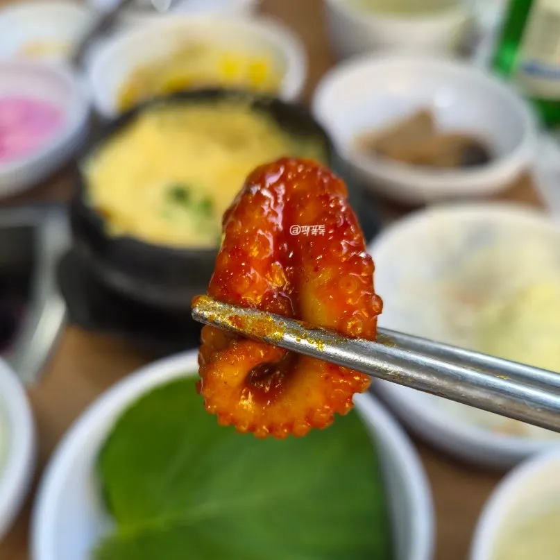 A piece of jjukkumi dipped in garlic sauce
