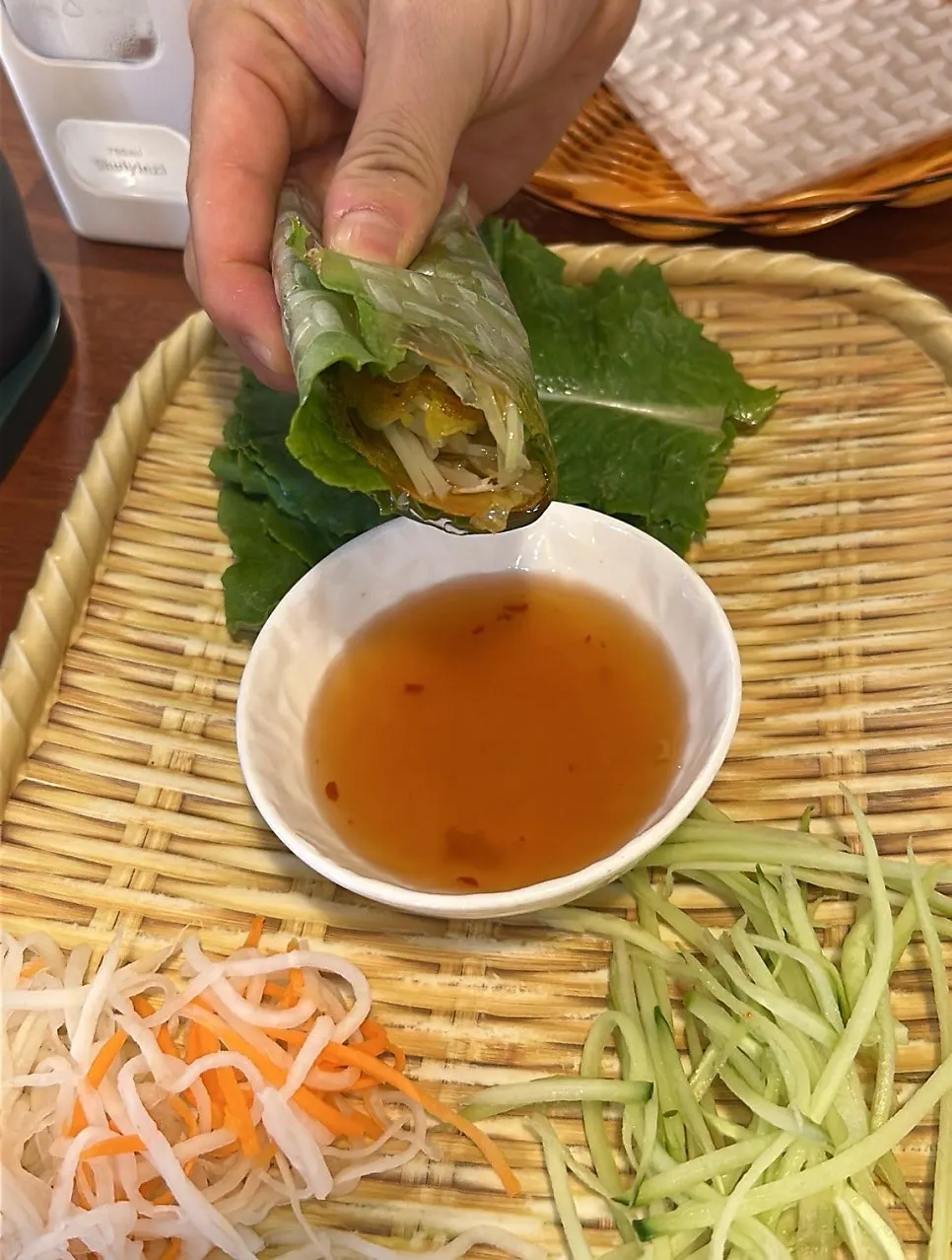 Rolled banh xeo wrap dipped into sauce