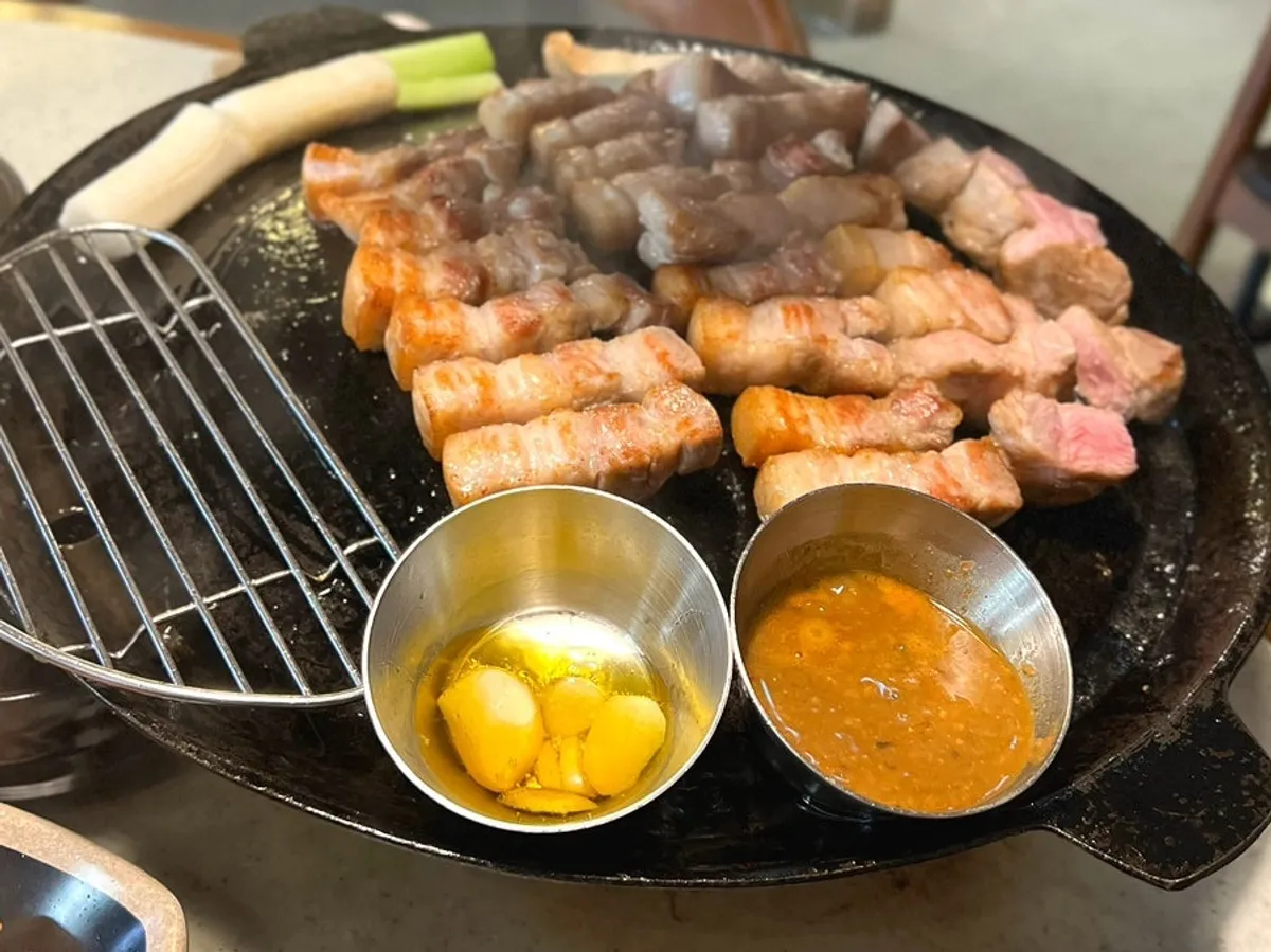 Pork belly and neck grilling on a cast-iron pan