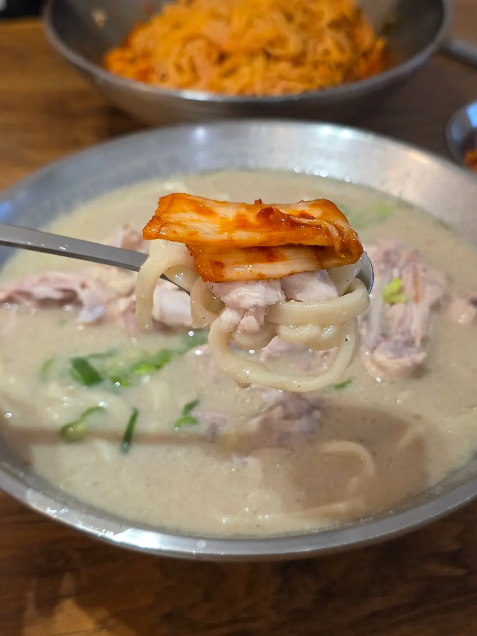 A bite of chicken kalguksu topped with silbi kimchi