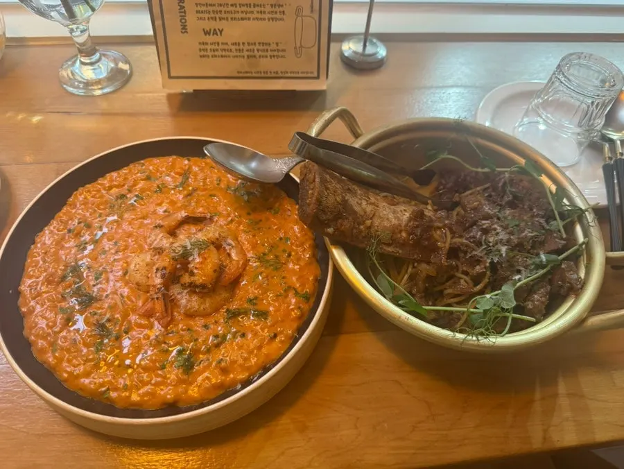 Table spread with galbi pasta in a tin pot and risotto in a porcelain bowl
