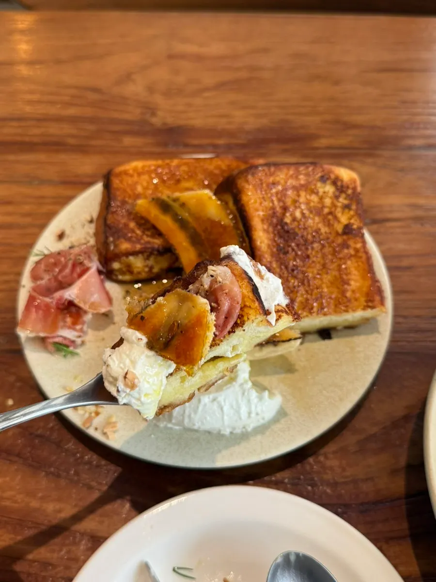 A bite of French toast topped with banana brûlée and ricotta