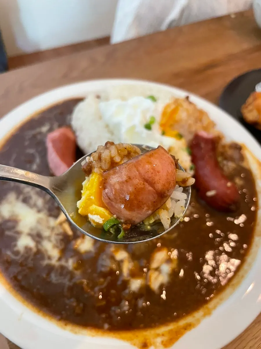 A bite combining sausage and curry together