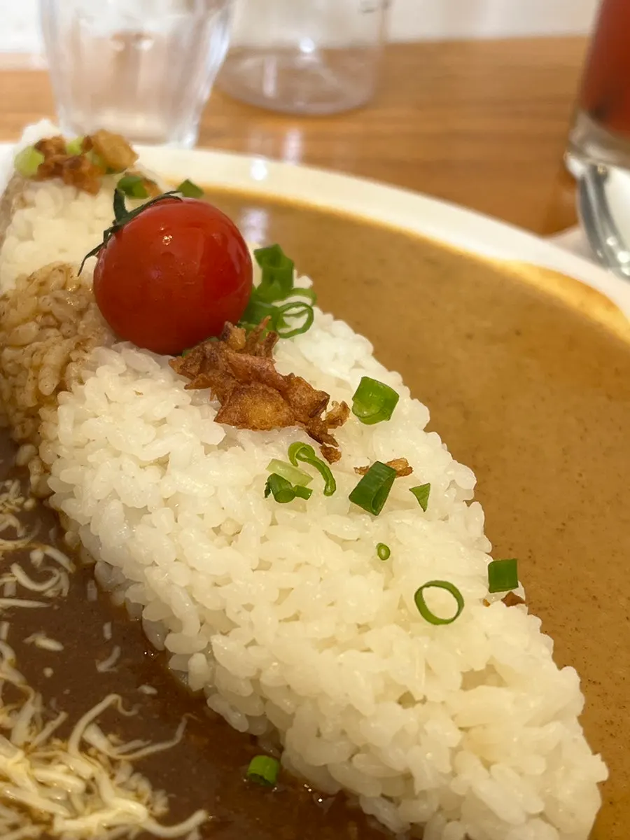 Half-and-half curry topped with cherry tomatoes and garlic flakes