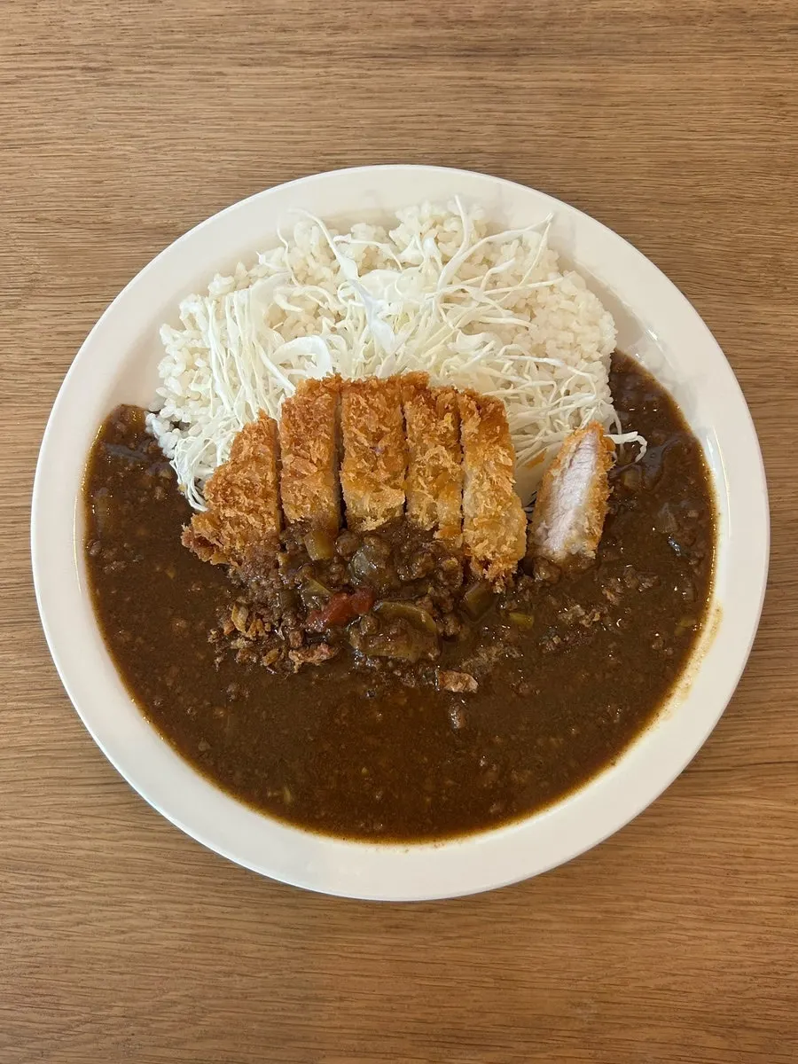 A plate of Sarugak Curry topped with tonkatsu and cabbage