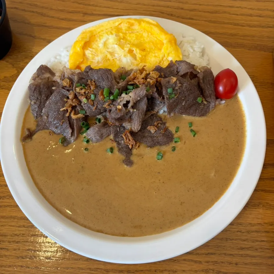A plate of brisket cream curry topped with scrambled egg