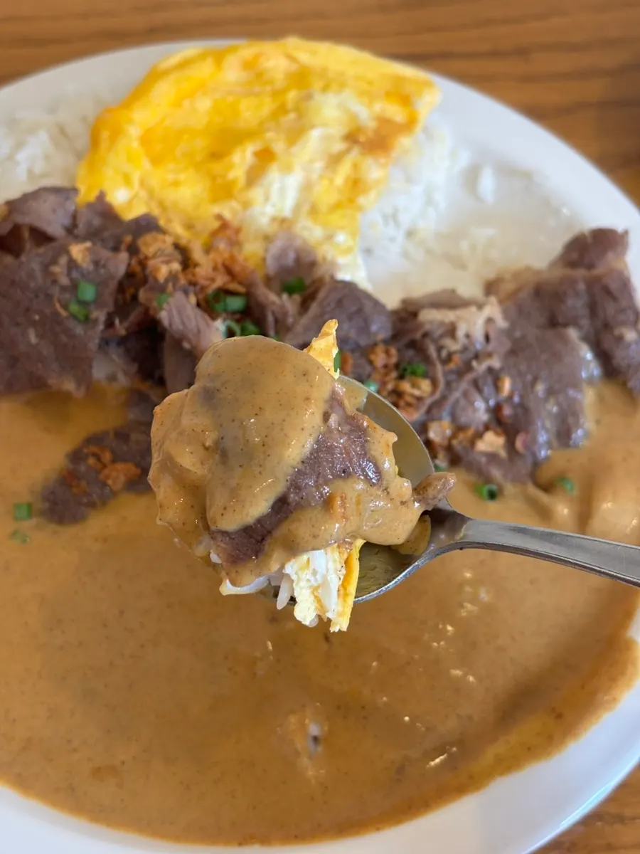 A spoonful scooping brisket and curry together