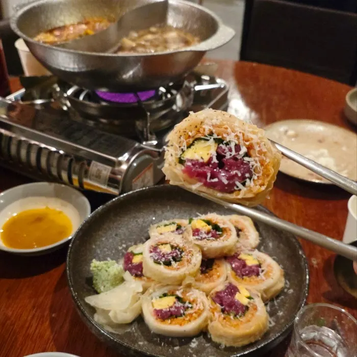 A piece of raw beef aged kimchi roll with sauce