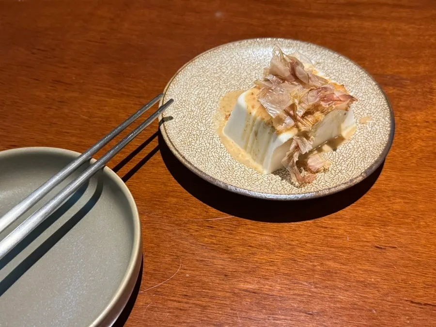 Basic side dish sundubu topped with sesame sauce and bonito flakes