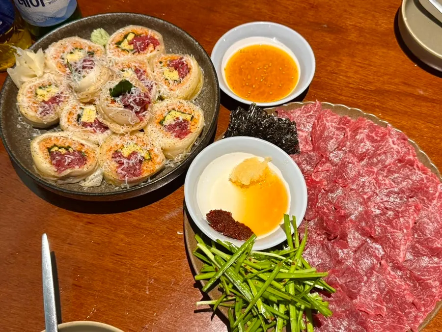 Table spread of raw beef kimchi roll and a full plate of mungtigi