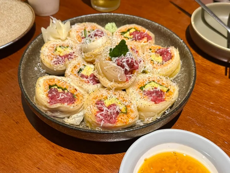 Raw beef kimchi roll served next to a somaek glass
