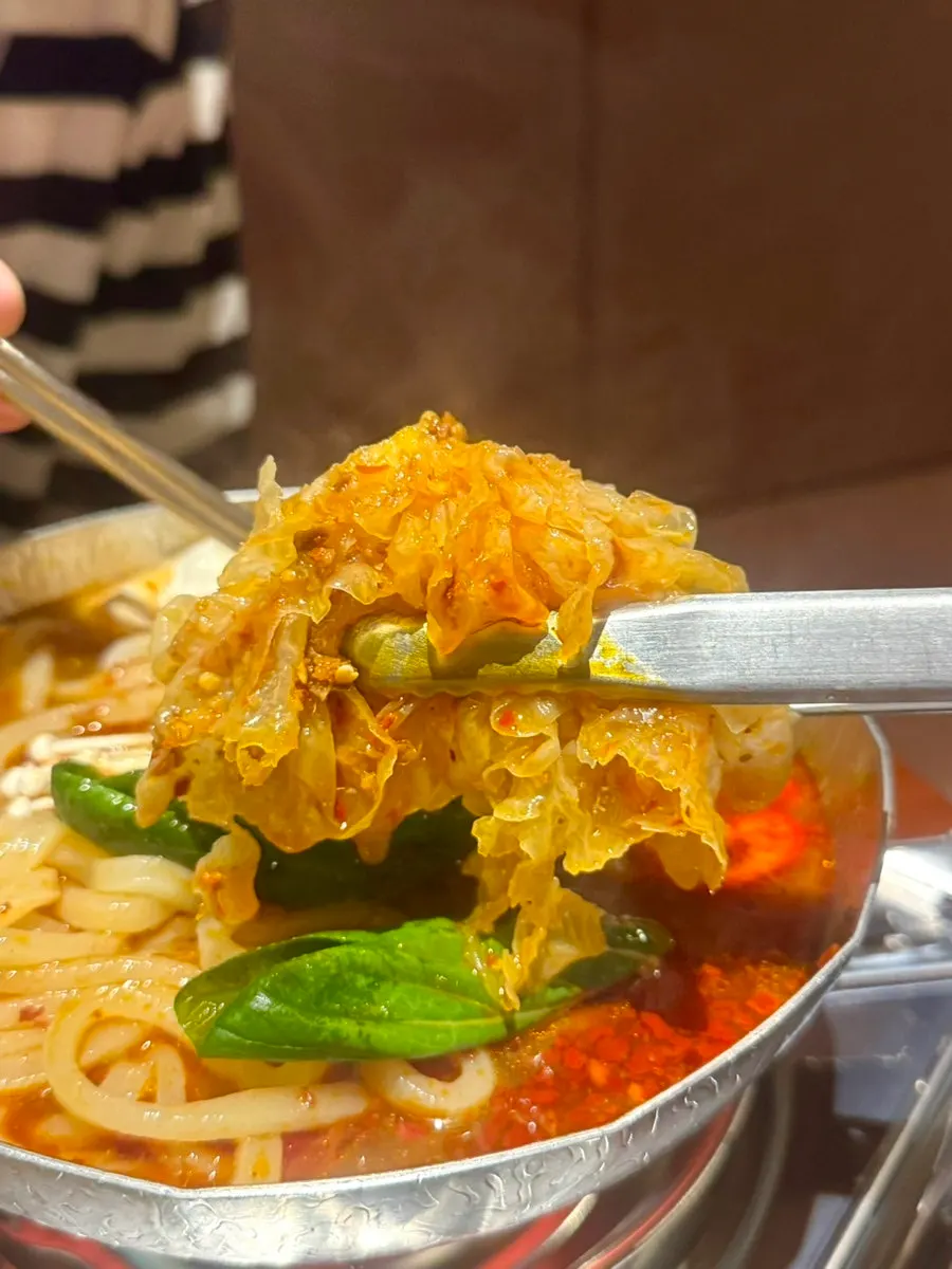Udon noodles lifted from the mala udon bowl