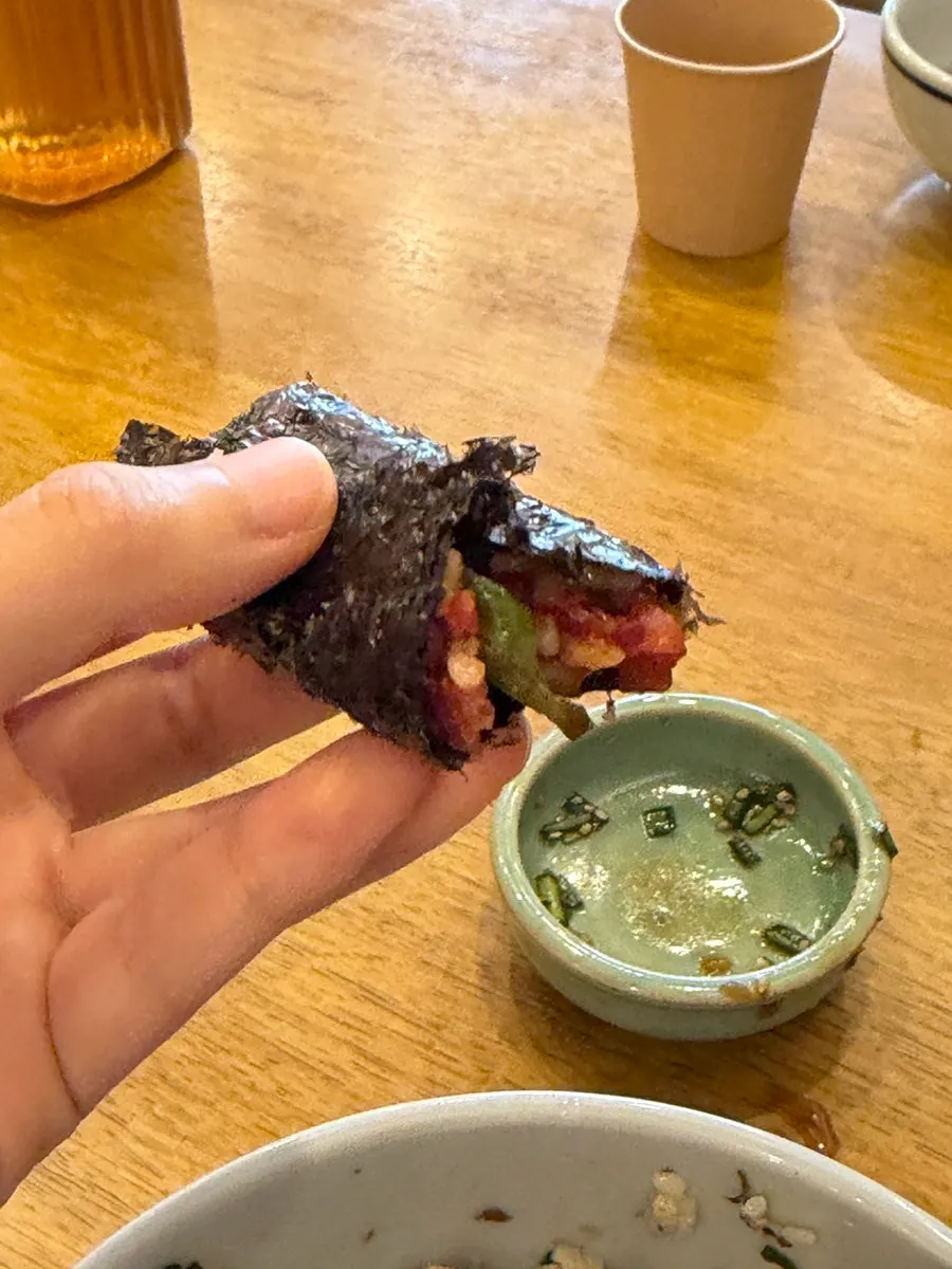 A bite of yukhoe bibimbap wrapped in gim