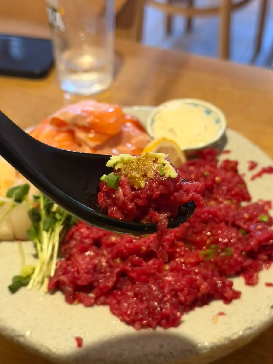A bite of beef tartare topped with wasabi and soy sauce