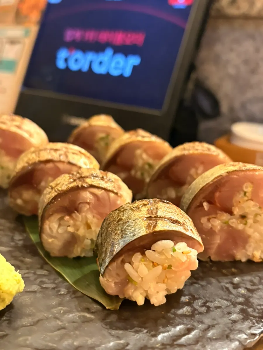 A plate of mackerel pressed sushi served first