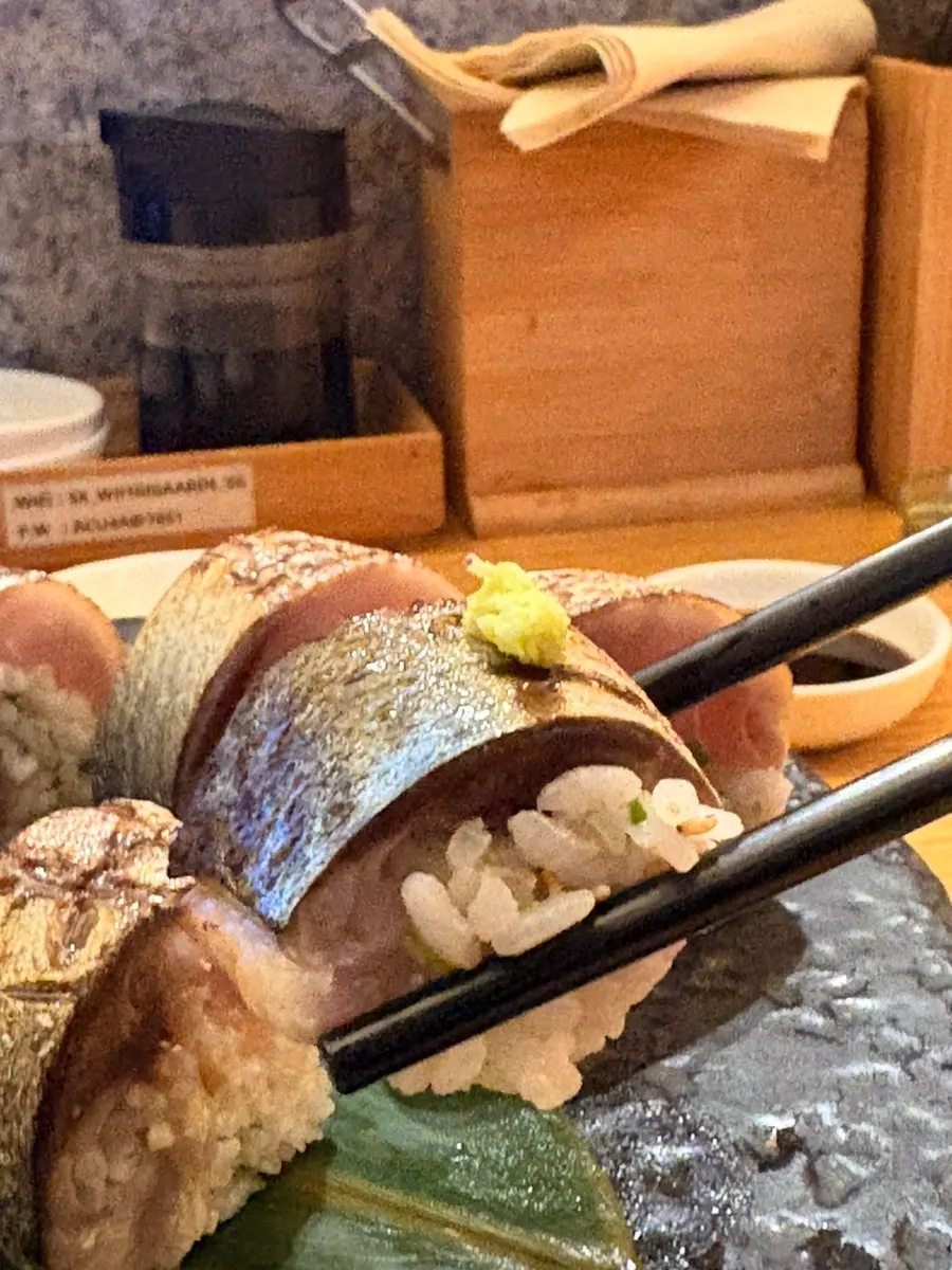 A piece of mackerel pressed sushi topped with wasabi