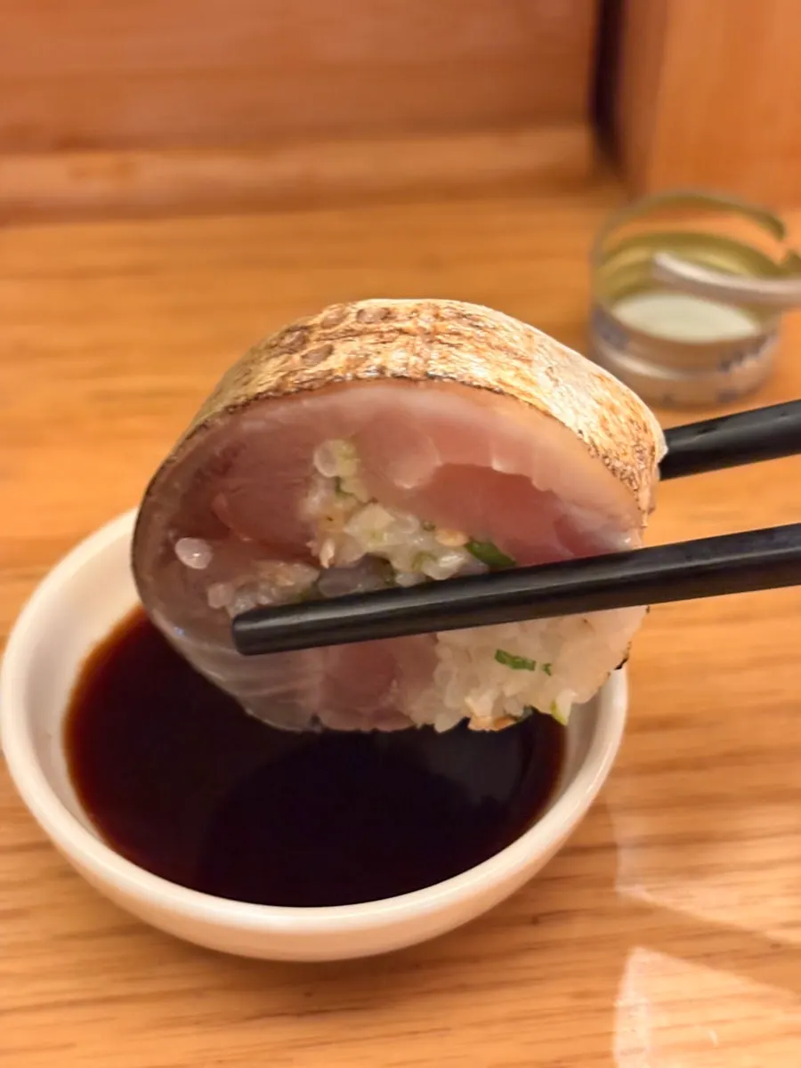 Mackerel pressed sushi dipped in soy sauce