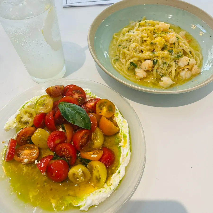 A bite of focaccia topped with ricotta cheese and tomato