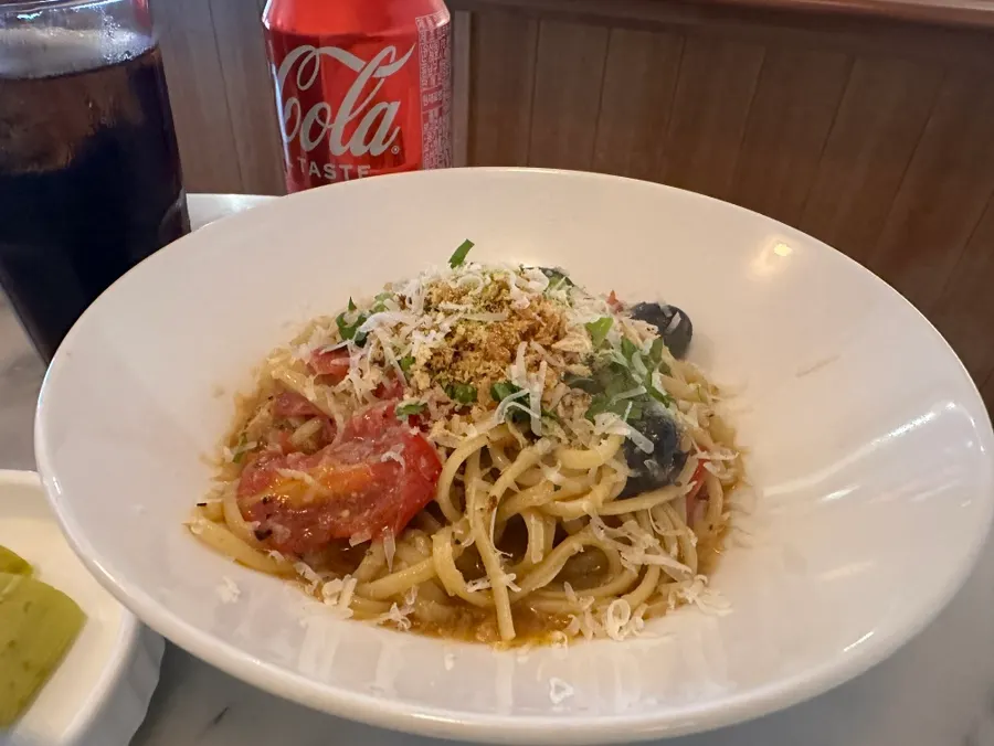 Puttanesca pasta topped with whole olives and pistachio