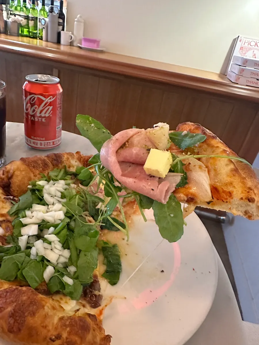 Slice of jambon-beurre pizza topped with arugula and jambon