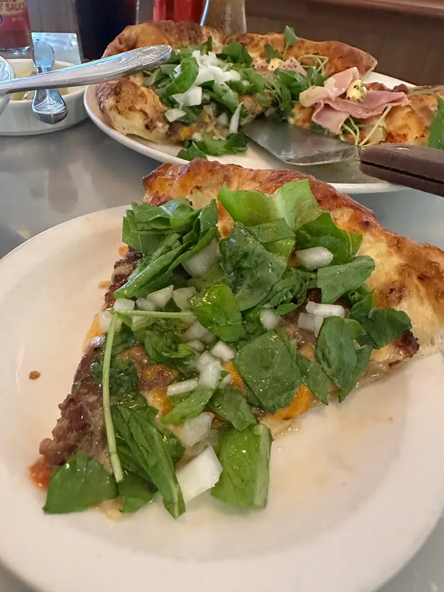 Beef cheeseburger pizza topped with beef, cheese, and romaine