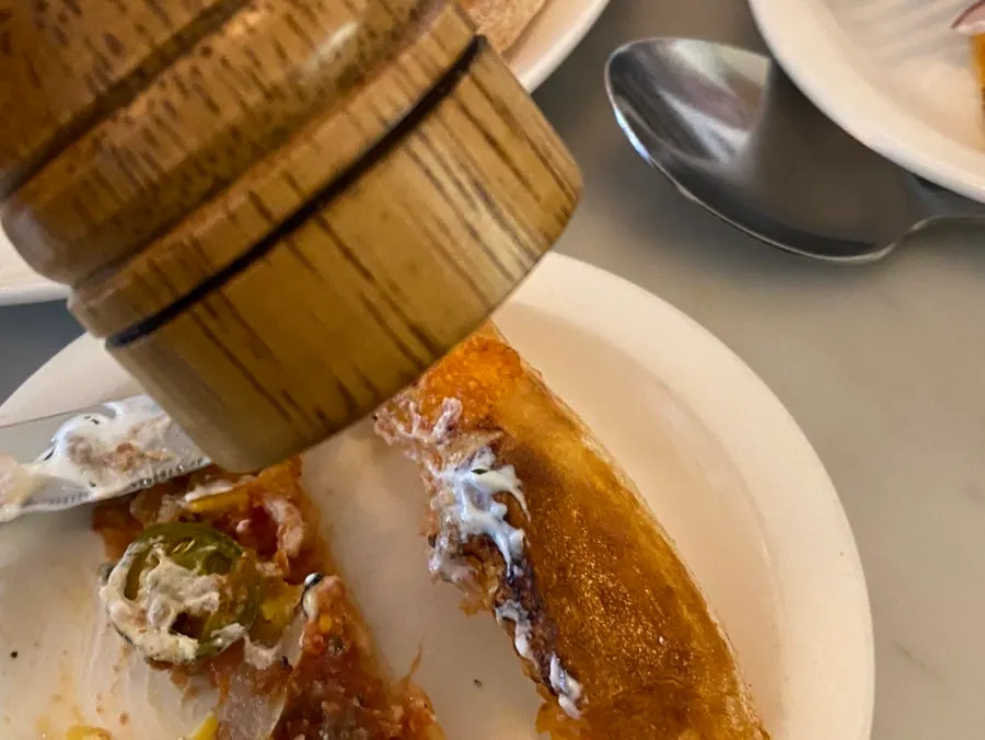 The crust ends of the pizza served with hot sauce and salt