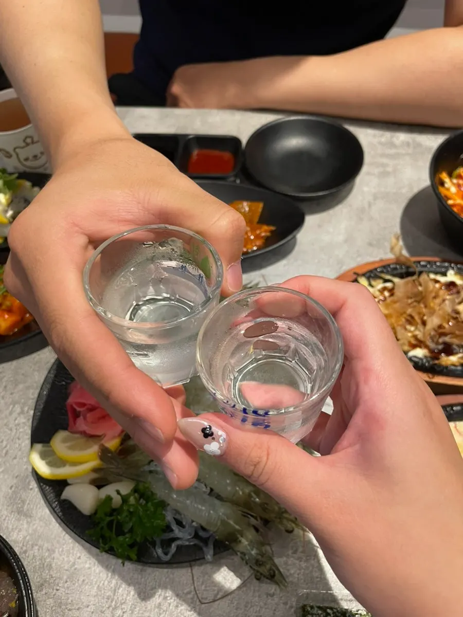 Salad tossed in vinegar-gochujang sauce alongside a glass of water
