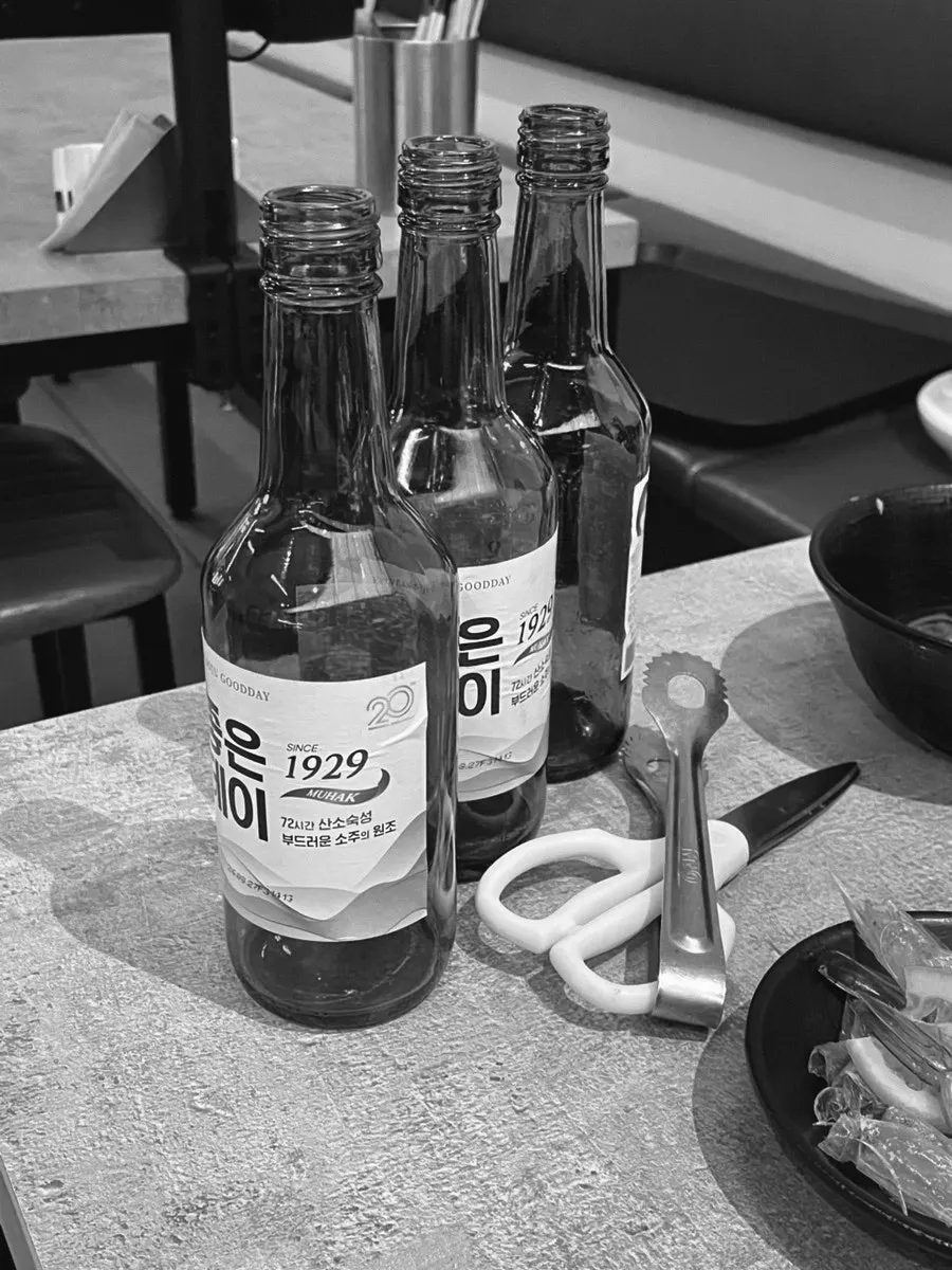 Nearly empty raw shrimp sashimi plate with soju bottles