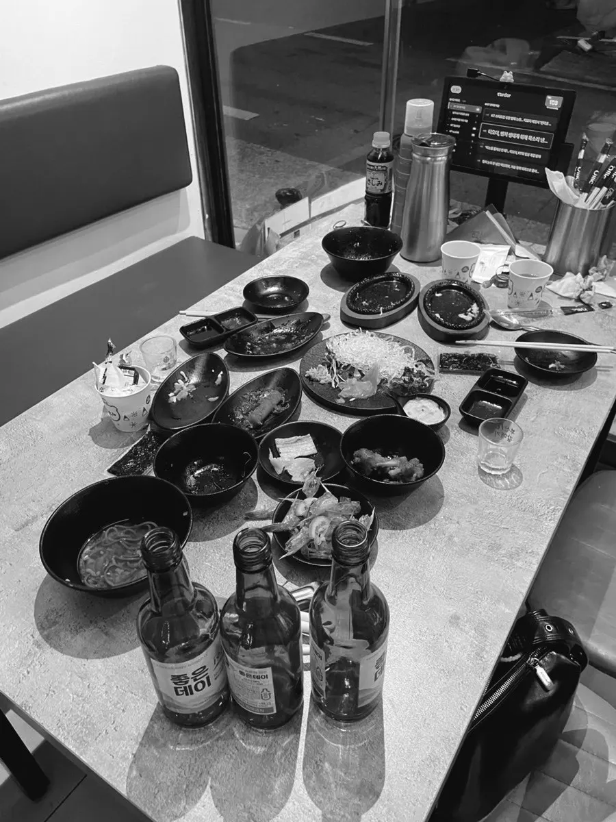 Three empty soju bottles and finished side dishes from the couple's meal
