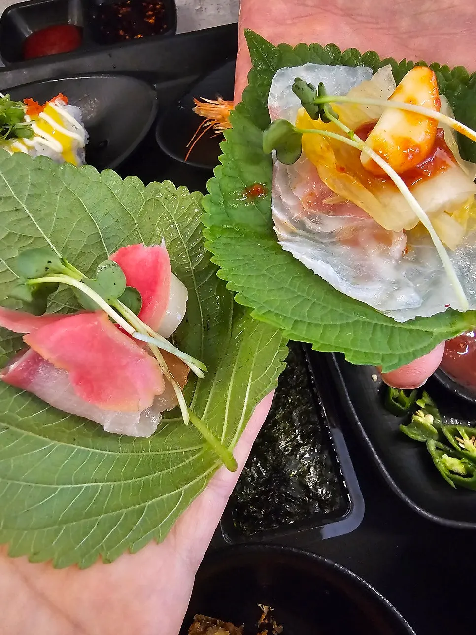 Two pieces of flatfish and amberjack piled on a lettuce wrap